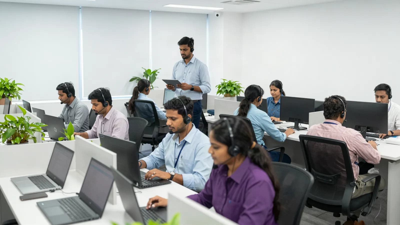 A customer support floor, agents in headsets answering chats at their desks